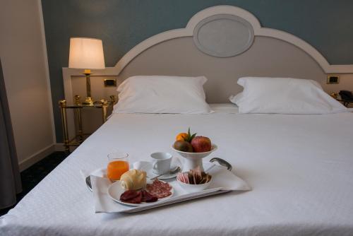 a breakfast tray with fruit and juice on a bed at Alli Due Buoi Rossi in Alessandria
