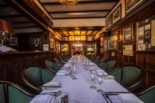 una lunga sala da pranzo con un lungo tavolo e bicchieri da vino di Petwood Hotel a Woodhall Spa