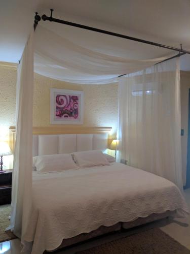 a bedroom with a white bed with a canopy at Hotel Pousada Laje de Itauna in Saquarema