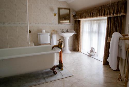 a bathroom with a tub and a sink at Petwood Hotel in Woodhall Spa