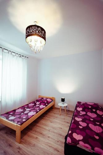 a bedroom with a bed with purple sheets and a chandelier at Miejskie Zacisze in Biłgoraj