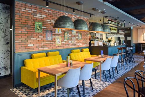 a restaurant with yellow chairs and tables and a brick wall at Ibis Szczecin Centrum in Szczecin