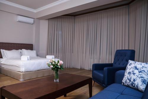 a hotel room with a bed and a blue chair and a table at Teryan Pushkin Apart Hotel in Yerevan