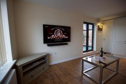 a living room with a table and a tv on the wall at Spacious Apartment with Roof Terrace, near The Waterfront, Ipswich in Ipswich