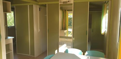 a room with a table and chairs and a mirror at Camping Les Foulons in Tournon-sur-Rhône