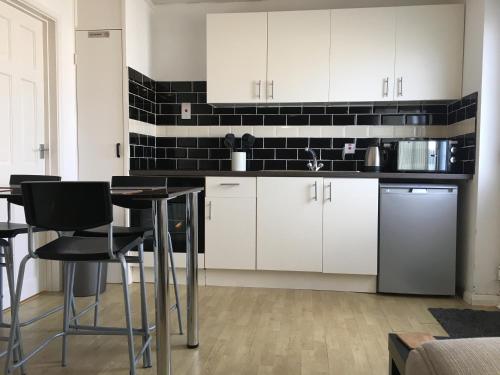 a kitchen with white cabinets and black tiles on the wall at 2 Bed Apartment w/private access to 7 miles of sandy beach - Sleeps 4 in Brean