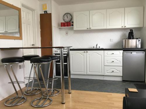 a kitchen with white cabinets and bar stools at Hill View Apartment in Brean