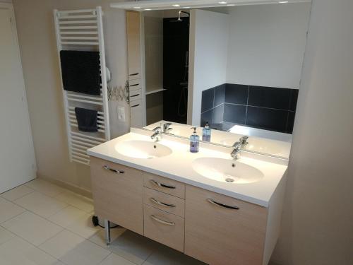 ein Badezimmer mit zwei Waschbecken und einem großen Spiegel in der Unterkunft Maison lumineuse in Les Herbiers