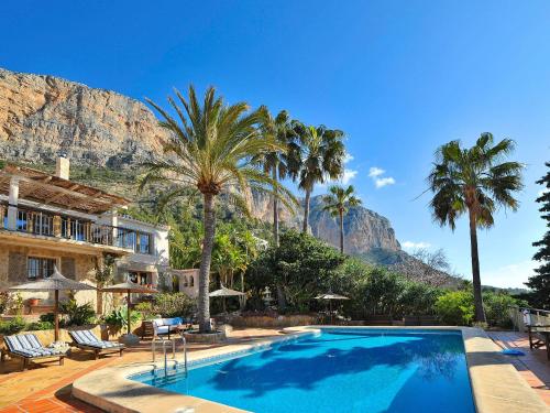 une piscine avec des palmiers et une montagne en arrière-plan dans l'établissement Holiday Home Petite Fleur by Interhome, à Montgo