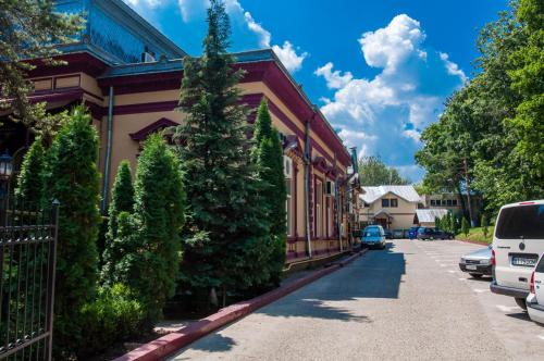 a building with a tree next to a street at Pensiunea Splendid in Dorohoi