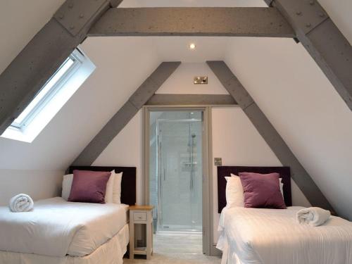 a attic room with two beds with purple pillows at Grosvenor House APT 2 in Aberystwyth
