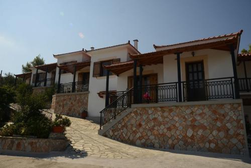 a large white house with a stone wall at Betsanis Stafylos Apartments in Stafylos