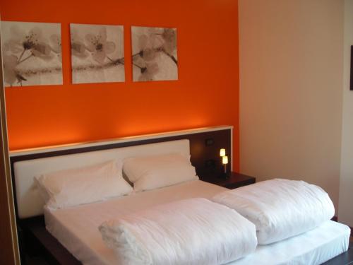 a bedroom with a white bed with an orange wall at Ely'S Residence in Romano D'Ezzelino