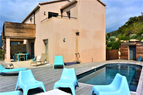 une villa avec une piscine et des chaises bleues dans l'établissement COLOMBA, à Conca