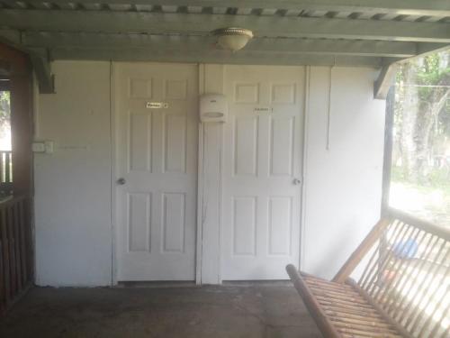a porch with two white doors and a bench at Hostal Villas Mexico in San Juan del Sur