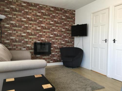 a living room with a couch and a brick wall at 2 Bed Apartment w/private access to 7 miles of sandy beach - Sleeps 4 in Brean