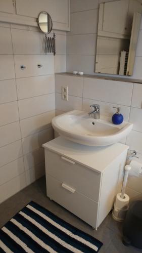 a white bathroom with a sink and a mirror at Ferienwohnung Gartenblick in Worpswede