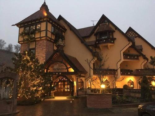 a large house with a christmas tree in front of it at Hotel Le Mandelberg in Mittelwihr