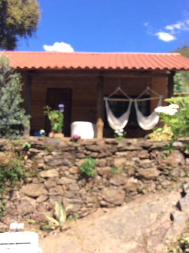 a house with a stone wall in front of a building at Unique Tiny House with Natural Building Techniques in Figueiró dos Vinhos