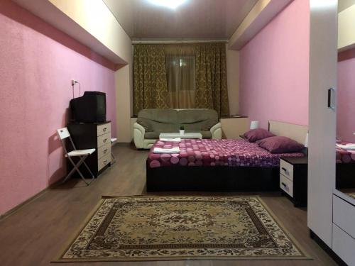 a bedroom with pink walls and a bed and a couch at Mini-Hotel Silver in Balashikha