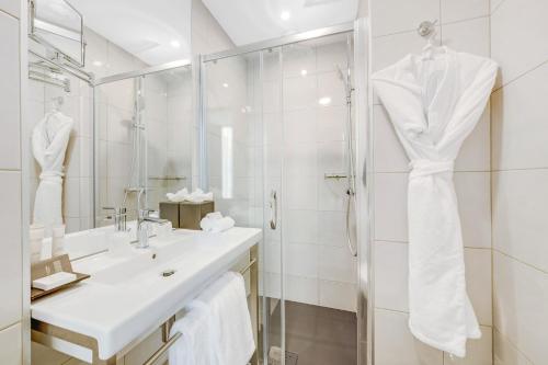 a white bathroom with a sink and a shower at Hôtel Villa Eiffel Mademoiselle in Paris