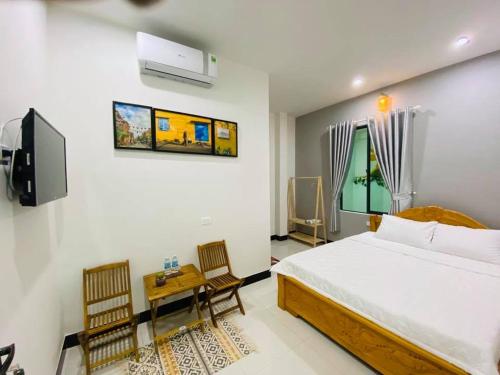 a bedroom with a bed and two chairs and a tv at NẮNG HOMESTAY in Tuy Hoa