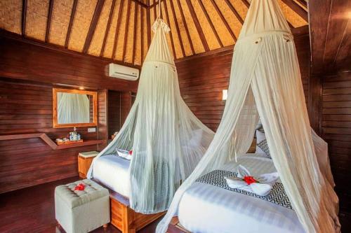 a bedroom with two beds with mosquito nets at Ocean Paradise Cottage in Nusa Lembongan