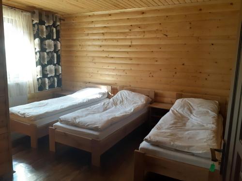 three beds in a room with wooden walls at Біла хата in Iltsi