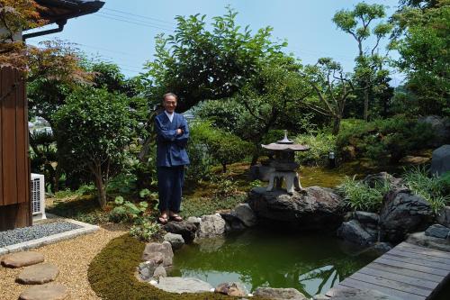 a man standing in a garden with a pond at Kotorian in Asuka