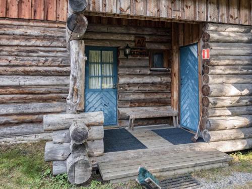 uma entrada para um chalé de madeira com uma porta azul em Holiday Home Vuokatinportti a7 by Interhome em Lahdenperä