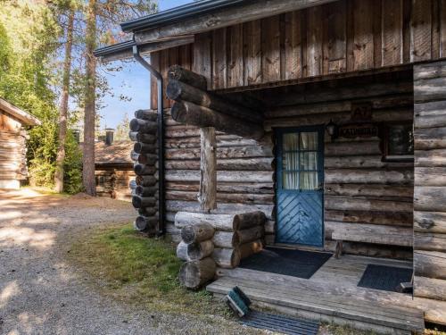 eine Blockhütte mit einer blauen Tür und einem Stapel Holzscheite in der Unterkunft Holiday Home Vuokatinportti a7 by Interhome in Lahdenperä