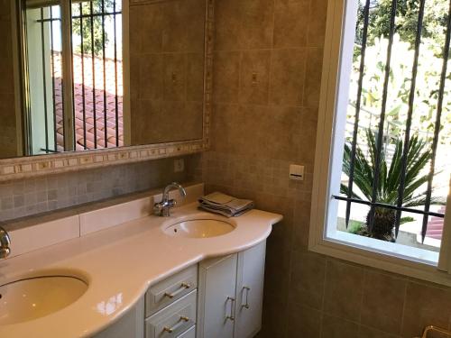 a bathroom with two sinks and a mirror and a window at Luxurious sea view villa in Saint Paul de Vence in Saint-Paul-de-Vence