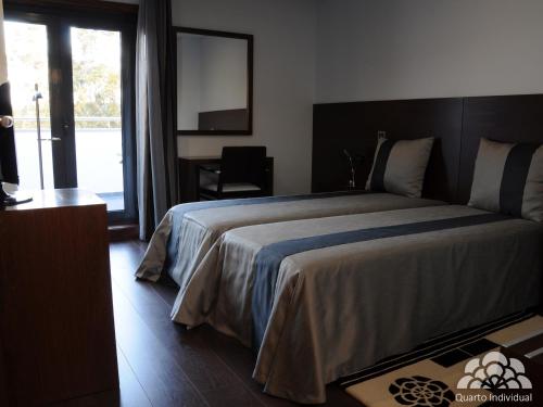 a bedroom with a large bed with a large window at Hotel Portas De Santa Rita in Ermesinde