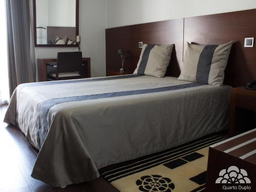 - une chambre avec un grand lit et une tête de lit en bois dans l'établissement Hotel Portas De Santa Rita, à Ermesinde