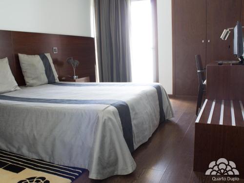 a bedroom with a large bed and a window at Hotel Portas De Santa Rita in Ermesinde