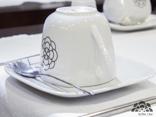 a white tea pot on a plate with a spoon at Hotel Portas De Santa Rita in Ermesinde