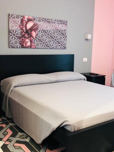 a bed in a bedroom with a painting on the wall at villa oltremare resort in Bagheria