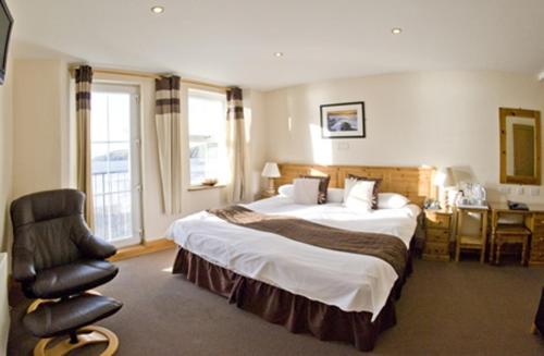 um quarto de hotel com uma cama grande e uma cadeira em Gwesty Ty Newydd em Aberdaron