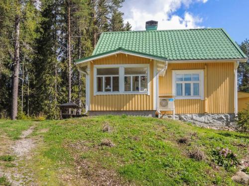 una pequeña casa amarilla con techo verde en Holiday Home Tyynelä by Interhome, en Varistaipale