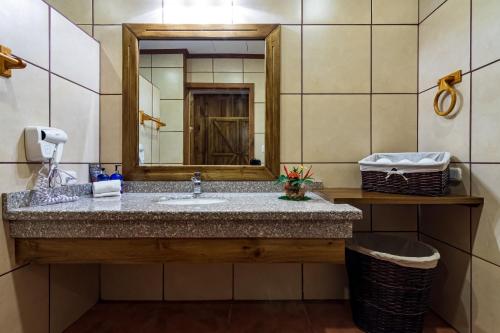a bathroom with a sink and a mirror at Hacienda Guachipelin Volcano Ranch Hotel & Hot Springs in Liberia