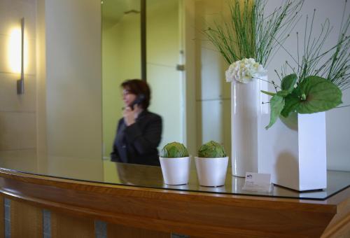 a woman talking on a cell phone and a vase with flowers at Olympic Hotel in Heraklio Town