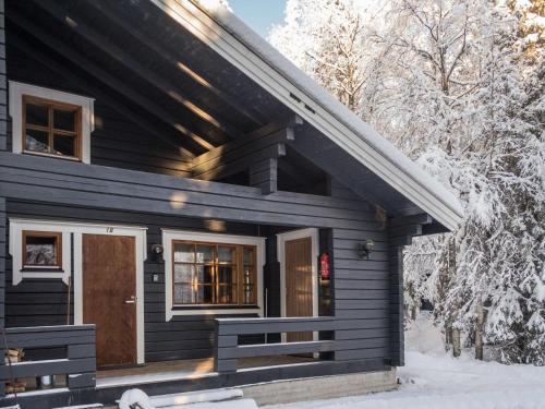 una casa negra con una puerta delantera en la nieve en Holiday Home Rukantaika 1b by Interhome en Virkkula