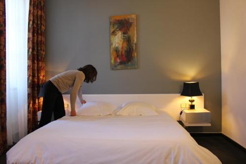 a woman standing on top of a bed at Hôtel Au Pavillon du Frêne in Lacaune