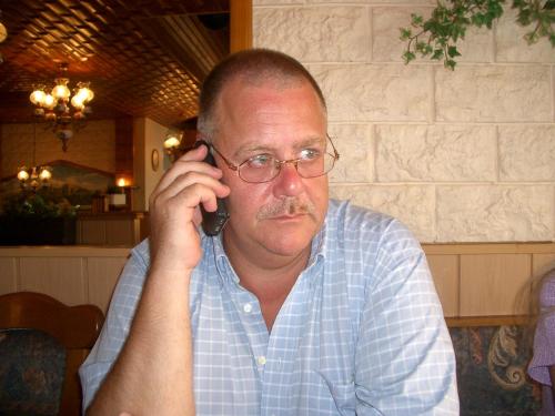 a man in glasses talking on a cell phone at Haus Thorwarth - Hotel garni in Cuxhaven
