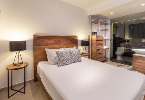 a bedroom with a large white bed and a bathroom at Riva 202 in Playa del Carmen