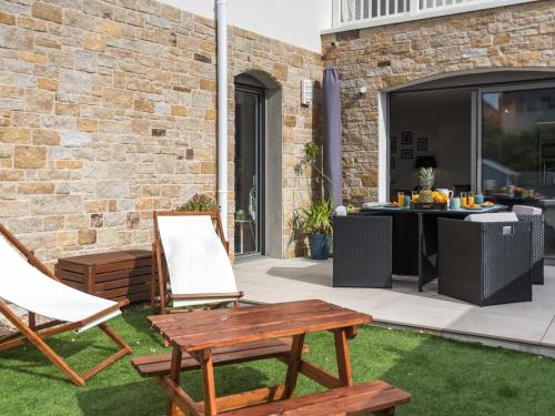 um pátio com uma mesa e cadeiras de madeira, uma mesa e uma mesa em Apartment Les Terrasses de la Plage-2 by Interhome em Quiberon