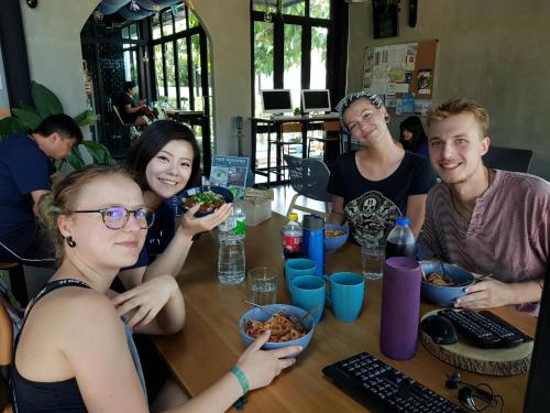 a group of people sitting around a table eating food at Wayha Hostel Don Mueang Airport in Bangkok