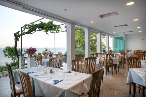 una sala da pranzo con tavoli, sedie e vista sull'oceano di Hotel Kaiser Bridge a Benitses