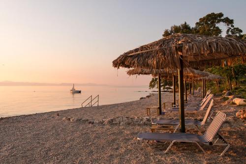 a group of chairs and umbrellas on a beach at Hotel Kaiser Bridge in Benitses