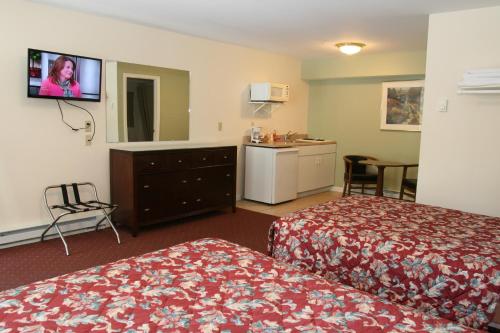 a hotel room with two beds and a tv on the wall at Studio Motel of Lake George in Lake George
